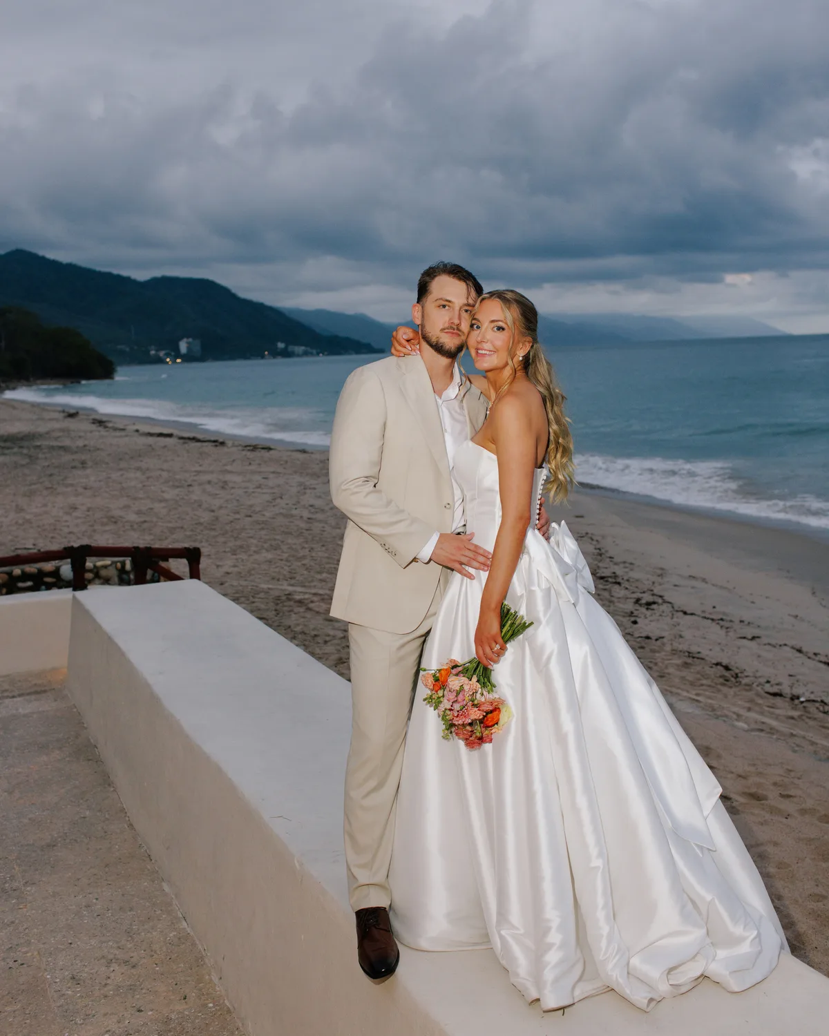 Bride and groom on the beach with the Sierra Madre behind them at Hotel Playa Fiesta Puerto Vallarta by Evgenia Kostiaeva